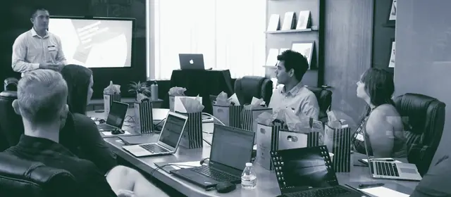 A presenter leading a small group working on laptops